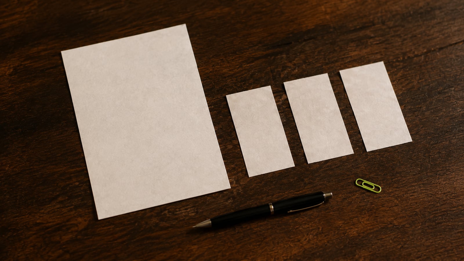 Blank invoice and separate paper slips arranged with a pen on a warm wooden desk.